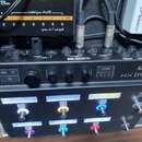 Černý kytarový procesor Line 6 HX EFFECTS s řadou ovládacích tlačítek a potenciometrů. Na panelu jsou viditelné nápisy „SAVE“, „ACTION“ a „MODE EDIT/…