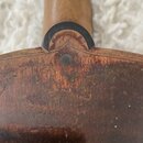 Detail zadní strany hřdelníku a horní části těla strunného nástroje z tmavého dřeva. Je vidět spojení krku s tělem a jeden viditelný šroub nebo hřebí…