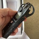 Černý digitální záznamový přístroj značky ZOOM s LCD displejem. Na boku jsou viditelné nápisy LINE IN, SETTING HOLD a DC5V u příslušných konektorů a…