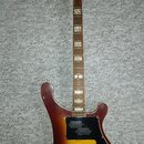 Elektrická kytara s tělem v barvě sunburst a hnědým hnedkem. Na hlavě je bílý nápis jolana a vedle něj menší text 3-55. Kytara má černý pickguard, dv…