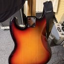 Zadní strana elektrické kytary s tělem v barevně sunburst (přechod od žluté k tmavě hnědé/černé). Na kovovédesce u krku je viditelné logo Fender. Kyt…