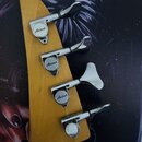 Záběr na zadní stranu dřevěné hlavy kytary s четыřmi chromovanými ladicími mechanismy. Tři z nich mají na krytce nápis „Aria Pro II“. Povrch dřeva i…