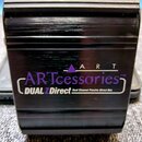 Černý kovový přístroj s vodorovným frézováním povrchu. Na přední straně je fialové logo ARTcessories TM a pod ním bílý nápis DUALZ Direct Dual Channe…