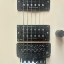 Detail těla kytary v krémové barvě se dvěma černými humbuckery. Na obou snímačích je bílý nápis DUNCAN DESIGNED. Dole je umístěn černý most s nápisem…