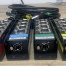 Čtyři černé kovové rozvodovací boxy s konektory. Každý box má na přední straně jeden kombinovaný XLR/jack konektor a čtyři symetrické výstupy. Boxy j…