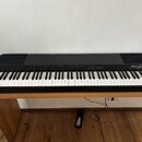 Černý digitální piano položené na dřevěném stole. Na pravé straně je bílý nápis YAMAHA a model PF80. Nástroj má standardní klávesnici s bílými a čern…