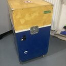 Modrý transportní case s horní dřevěnou částí, osazený kovovými rohy a zámkem. Na horní části je zelená nálepka s nápisem VYBRAT CLO a červenobílá va…