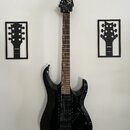 Černá elektrická kytara s hrotovitou hlavou a tmavým hnedým hmatníkem. Na hlavě je bílý nápis Xcart. Kytara má dva humbuckery, tremolo systém a je um…