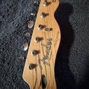 Hlava elektrické kytary z přírodního dřeva s chromovanými ladičkami. Na povrchu je černý nápis Fender, pod ním text MADE IN MEXICO a vedle něj nápis…