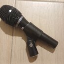 Černý dynamický mikrofon s kovovou mřížkou a držákem. Na těle mikrofonu je vyražen nápis AUDIX. Povrch je matně černý s viditelnými stopami používání…