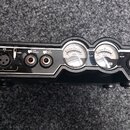 Černý elektronický přístroj s ovládacím panelem. Jsou zde dva XLR vstupy označené 1/L a 2/R, přepínač +48V, přepínače NORM a PAD oraz dva analogové V…