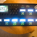 Černý kytarový procesor s displejem a ovládacími tlačítky. Na horní části je nápis FRACTAL AUDIO SYSTEMS a model FM9 AMP MODELER / FX PROCESSOR - MAR…
