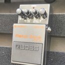 Kytarový efekt pedál značky BOSS, model Metal Zone MT-2. Zařízení má šedý kovový kryt s oranžovými nápisy a čtyři ovládací knoflíky. Na horní části j…