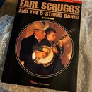 Kniha s černým obalem a červeným horním okrajem. Na předsłówce je nápis REVISED AND ENHANCED EDITION a název EARL SCRUGGS AND THE 5-STRING BANJO By E…