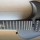 Černá elektrická kytara s matným povrchem. Na hmatníku je viditelné bílé logo ve tvaru stylizovaného ptačího křídla. Nástroj má dva humbuckery s bílý…