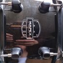 Černý buben s lesklým povrchem a kovovými obručmi. Uprostřed je umístěno logo s nápisem MAPEX a textem MPX MAPLE. Na povrchu jsou viditelné odrazy ok…