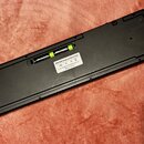 Spodní strana černého plastového USB MIDI Keyboard Controller. Na bílé nálepce je uveden nápis USB MIDI Keyboard Controller, značky CE, FC a sériové…