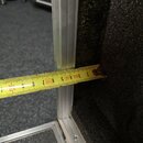 Fotografie zachicuje detail vnitřku transportního kufru s hliníkovými profily a černou pěnovou výplní. K měření vnitřního prostoru je použit žlutý me…