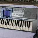 Stříbrný digitální klavír s nápisem YAMAHA a označením modelu PSR 1500. Nástroj má displej, početné ovládací tlačítka a pravý reproduktor za mřížkou.…