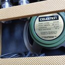Detail reproduktoru značky CELESTION v olivově zeleném provedení. Na štítku je uveden Model number G12 M, Power capacity 25 WATTS, Impedance 8 OHMS a…
