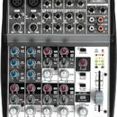 Míchací pult s nápisem XENYLYX 1002 a logem BEHRINGER. Zařízení má šedé tělo s černými ovládacími prvky, obsahuje dva mikrofonní vstupy XLR a řadu li…