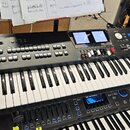 Černý digitální klavír značky Roland s nápisem BK-9 BACKING KEYBOARD. Nástroj má klávesnici, několik řad tlačítek a dva displeje v horní části. V pop…