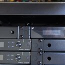 Černý rackový case, ve kterém jsou namontovány tři bezdrátové přijímače značky SENNHEISER s označením XS WIRELESS 2. Každý přijímač má displej, ovlád…