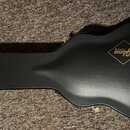 Černý tvrdý kufr na kytaru v akustickém tvaru. Na povrchu je umístěno dvě žlutá loga ve tvaru kosočtverců s nápisy Epiphone a Gibson CUSTOM. Kufr je…