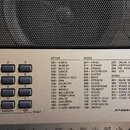 Detail ovládacího panelu elektronického klavíru v stříbrné barvě. Na panelu je vidět nápis PSR E443 a různé ovládací tlačítka, včetně sekcí Category,…