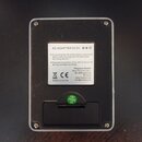 Zadní strana stříbrného efektového pedálu s černým plastovým krytem baterie. Na bílé nálepce je text AC ADAPTER DC9V, varovné pokyny k baterii a údaj…