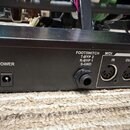 Detail zadní strany černého elektronického zařízení. Jsou zde vidět konektory s nápisy POWER, FOOTSWITCH (T-BYP 2, R-BYP 1, S-GND) a MIDI (IN, OUT /…