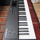 Černý digitální klavír s bílými a černými klávesami. Na levém boku je svisle napsáno logo studiologic a v horní části nápis SL88 GRAND PIANO. Ovládac…