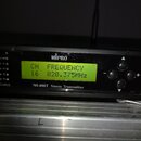 Černý elektronický přístroj s nápisem MiPro a označením MI-808T Stereo Transmitter. Zařaďovací displej zobrazuje text CH FREQUENCY 16 820.375MHZ. Na…