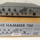 Šedý basový předzesilovač s nápisem Aguilar TONE HAMMER 700. Na předním panelu jsou ovládací knofíky Gain, Mid Level, Bass, Drive, Mid Freq, Treble a…