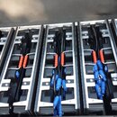 Otevřený transportní kufr s vnitřním členěním, ve kterém jsou uloženy černé elektronické moduly. K modulům vedou černé kabely zakončené modrými konek…