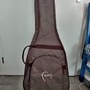 Hnědý polstrovatý pouzdro (gig bag) na kytaru s ramenním popruhem. V dolní části je bílý nápis „-Faith“. Povrch materiálu vykazuje mírné pomačkání.