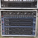 Dvě stohované rackové skříně s audio vybavením. Horní rack obsahuje dvě jednotky značky Lc electronic a jeden grafický equalizér RANE. Spodní rack ob…