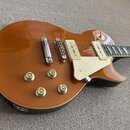 Elektrická kytara s hnědým lesklým povrchem a bílým plechtrátem. Nástroj má dva humbuckery s krémovými kryty, čtyři zlaté otočné knoflíky a chromovan…