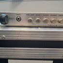 Kovový rackový přístroj stříbrné barvy s nápisy MODEL PSA-1.1 a TECH 21 NYC. Na předním panelu se nachází vstup INPUT, pět otočných potenciometrů s p…