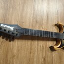 Elektrická kytara s přírodním dřevem na okrajích a tmavým, žilnatým povrchem středu těla. Na hlavě je bílý nápis Ibanez. Nástroj má šest strun a čern…