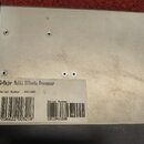 Fotografie zachycuje spodní stranu šedého kovového zařízení. Na bílé nálepce je uveden text G-Major Multi Effects Processor a Serial Number 3411305.…