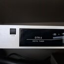 Detailní pohled na přední panel stříbrného digitálního tuneru. Na černém displeji je bílý nápis DTR-2 a DIGITAL TUNER, vpravo jsou vidět hodnoty -50,…