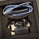 V černé krabici s pěnovým vložkem je světle modrý USB kabel a černý napájecí adaptér s přívodním kabelem. Na modrém kabelu je čitelný nápis 2725 80°C…