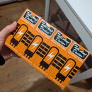 Čtyři oranžové papírové krabičky s černým potiskem. Na každé je nápis Tube Amp Doctor™, SELECTED TUBES PREMIUM QUALITY a adresa www.tubeampdoctor.com…