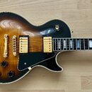 Elektrická kytara s tónem sunburst a tmavým hnedým okrajem. Má dva humbuckery se zlatými kryty, zlatý most a stopku, černý pickguard a čtyři černé ov…