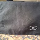 Černý textilní pouzdro obdélníkového tvaru. V pravém dolním rohu je bílý oválný nápis "Amp Bag ®". Povrch materiálu vykazuje mírné pomačkání.