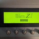 Detailní záběr na ovládací panel syntetizátoru s podsvíceným displejem. Na displeji je text MULTI OSCILLATOR SYNTHESIZER, označení Z1 a značka KORG.…