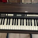 Hnědý elektronický orgán s klaviatura v dřevěném provedení. Na ovládacím panelu jsou nápisy XK-2 a HAMMOND. Jsou zde vidět bílé klávesy, tahové přepí…