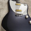 Tmavě šedá elektrická kytara s bílým plechovým pickguardem. Nástroj má dva žluté humbuckery a dvě bílé oválné ovládací knoflíky. Na těle nejsou vidit…