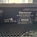 Detail zadní strany černého hudebního zesilovače s mřížkou. Je zde vidět logo Blackstar a nápis Designed and Engineered by Blackstar Amplification Lt…